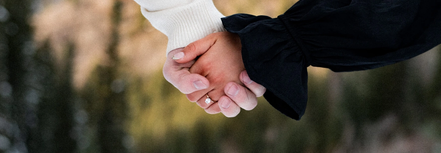 Close-up of an engaged couple holding hands outdoors during winter